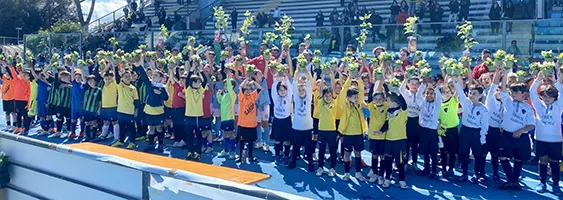 gruppo di bimbi giocatori di calcio, in uno stadio, nella fase di premiazione con mani alzate e coppe con in alto delle nuove